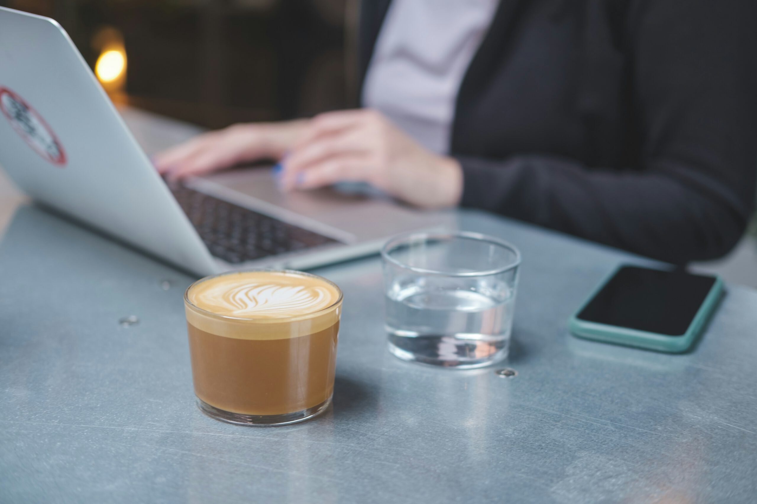 Beispielfoto für eine Kundin, die gemütlich bei einer Tasse Cappucino eine psychologische Online Beratung am Laptop erhält.